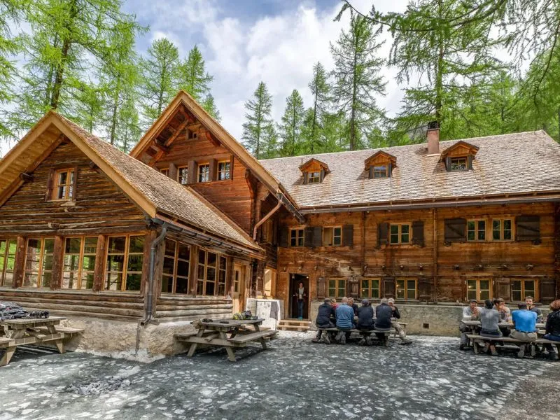 Du khách nghỉ ngơi và thưởng thức ẩm thực tại căn chalet gỗ truyền thống trong khu vực Vườn quốc gia Thụy Sĩ